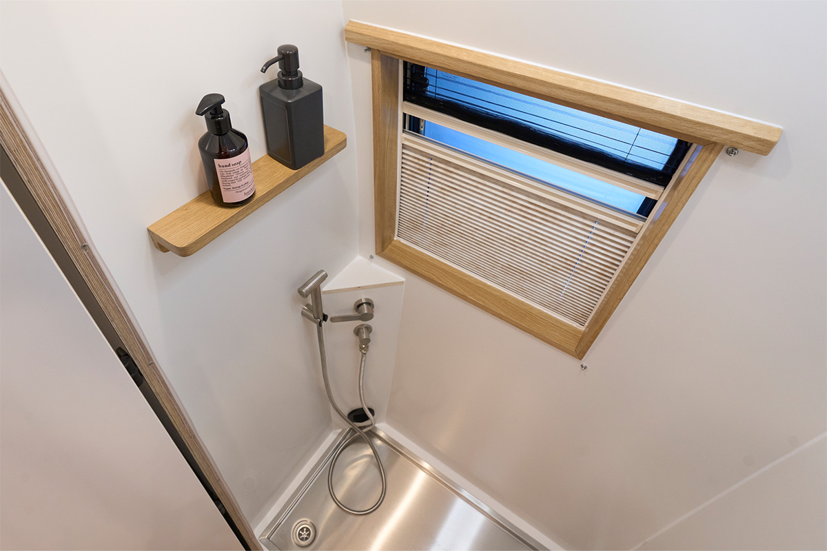 Dometic S7 hinged window in the bathroom with self-developed splash guard. Stainless steel shower tray with 900 x 600 mm special dimensions and two outlets. 