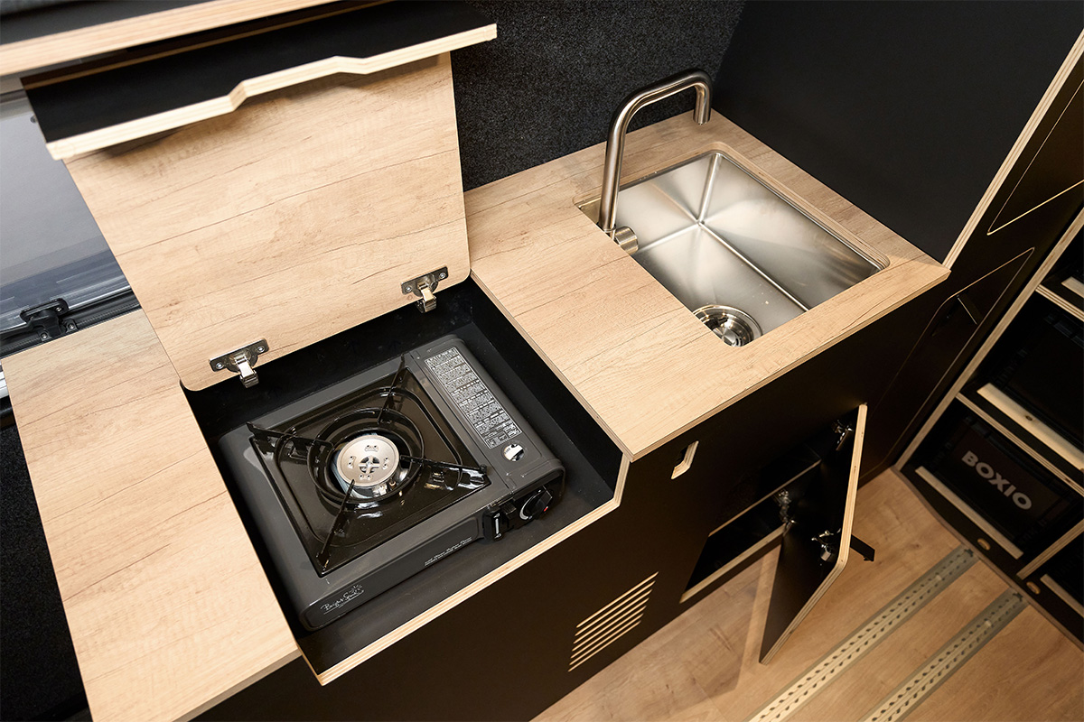 1-burner gas cartridge stove, hidden in the furniture under a flap. Stainless steel washbasin with fold-down tap. 